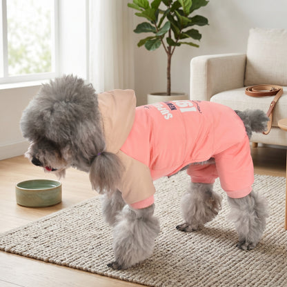 Poodle wearing a pink CozyCloud full-body jumpsuit with a hood, standing on a soft rug in a modern living room.