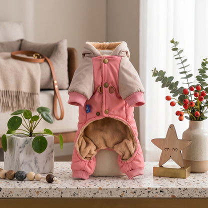 CozyCloud Full-Body pink dog jumpsuit with a hood and warm interior lining, standing on a decorative surface next to a star-shaped ornament.