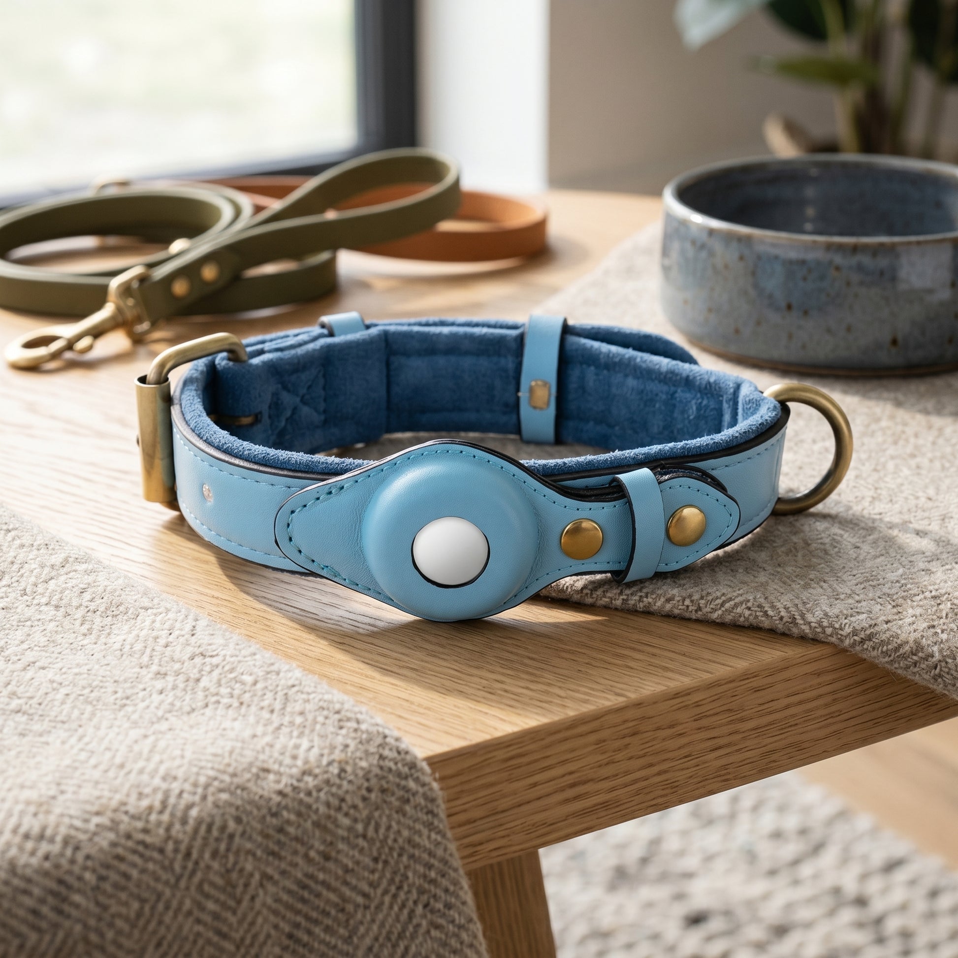 Nordic Guardian genuine leather dog collar in light blue with integrated secure AirTag holder and polished metal hardware on a wooden surface.