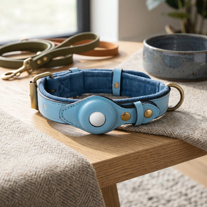 Nordic Guardian genuine leather dog collar in light blue with integrated secure AirTag holder and polished metal hardware on a wooden surface.