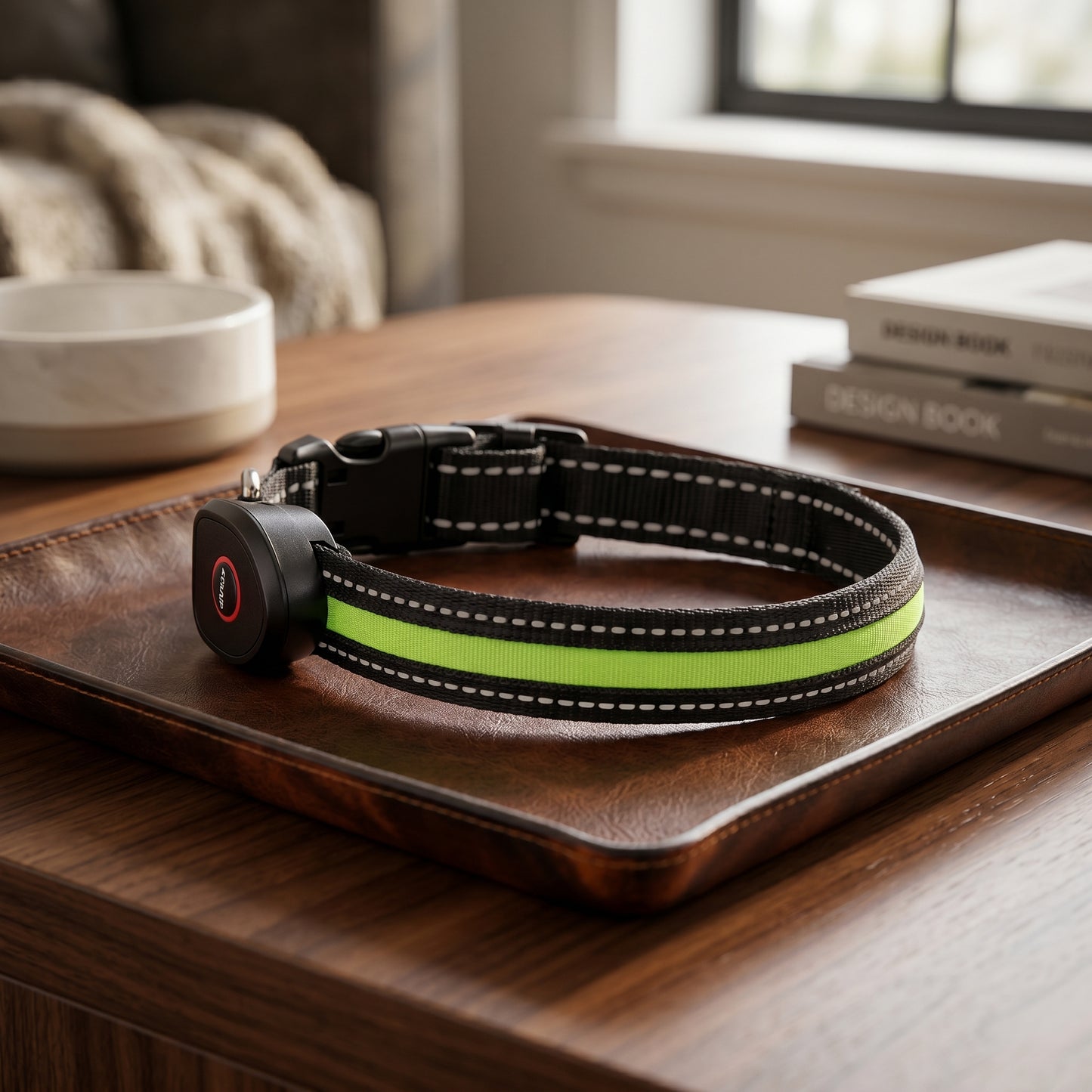 A black dog collar with a reflective neon green strip displayed on a brown leather tray on a wooden table.
